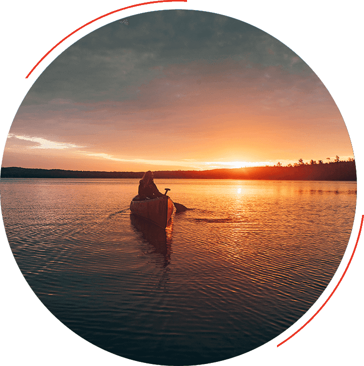 A person in a canoe on the water at sunset.