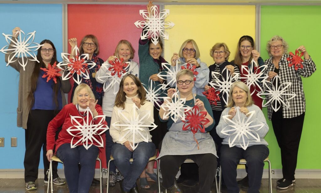 Group holding paper snowflakes, colorful background.