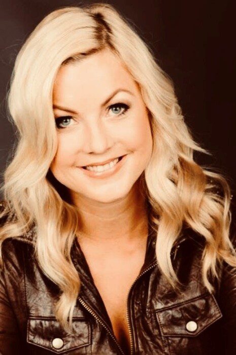 Smiling woman with blonde hair and jacket.