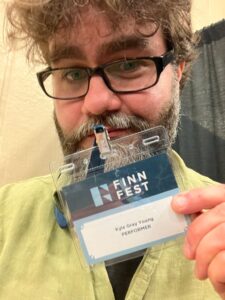 a9b9c98e-f754-4a3b-9ecd-df7e265b7ea1_768x1022 Man holding Finn Fest performer badge.